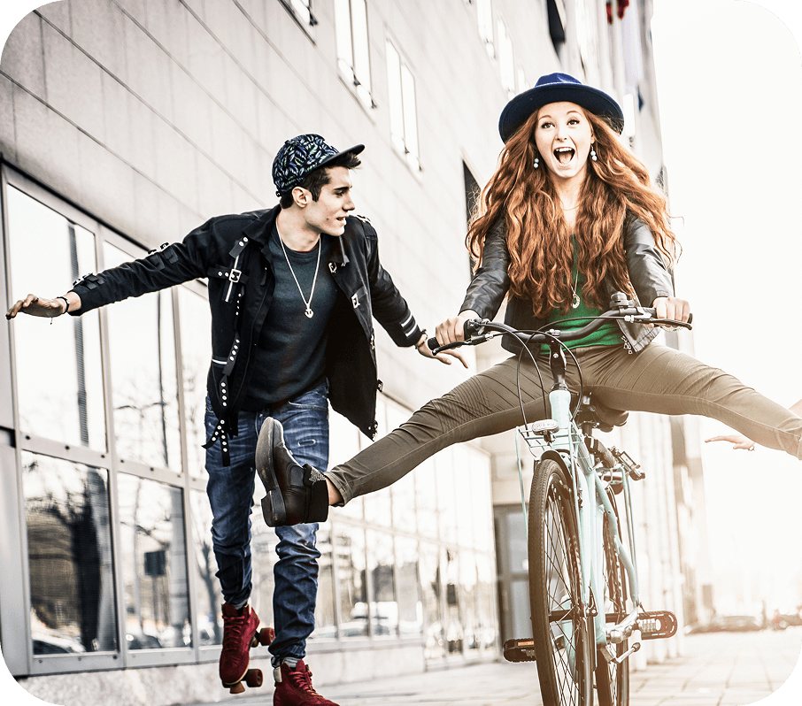 Un groupe de jeunes ensemble sur le trottoir, dont un qui fait du vélo.