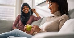 Teens sitting together. One of them is holding a pear