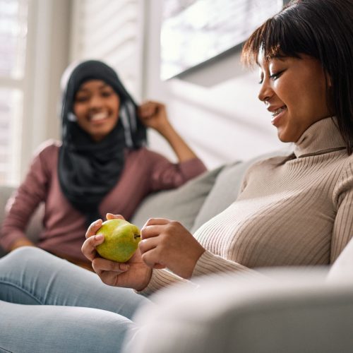 Teens sitting together. One of them is holding a pear